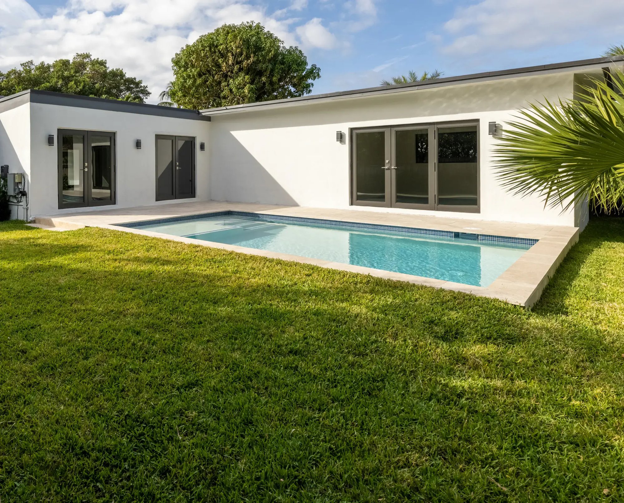 A stunning modern home featuring a refreshing fibreglass pool and lush green grass, perfect for relaxation and outdoor gatherings.