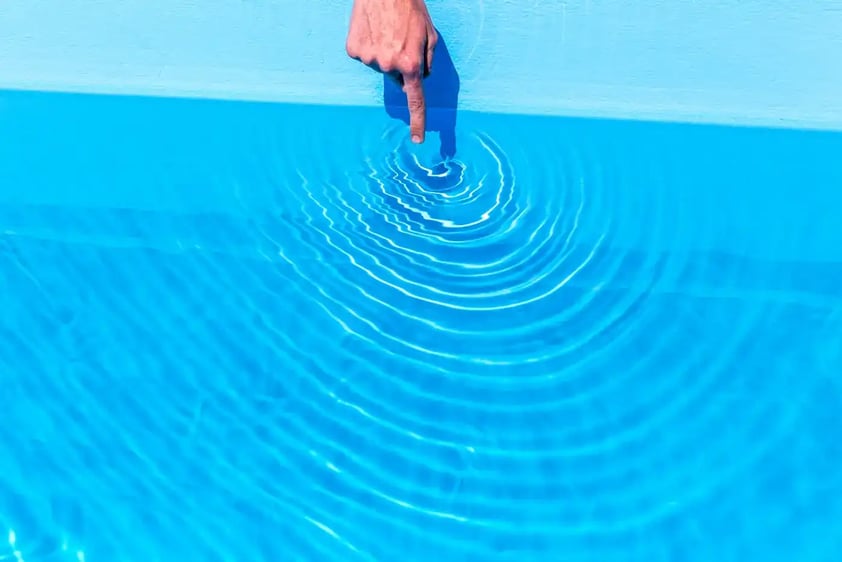 Person testing the temperature of the swimming pool water